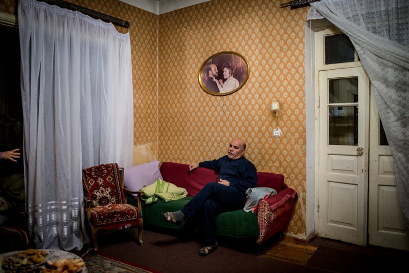 56-летний Хачик в гостиной дома, который его семья снимает в Ереване. На стене висит свадебная фотография Хачика и его супруги — единственная вещь, которая осталась у семьи на память о Сирии. У Хачика больное сердце. Он молча слушает, как жена рассказывает о бюрократических сложностях, которые ей пришлось преодолеть, чтобы выхлопотать мужу бесплатное медицинское обслуживание