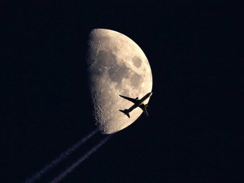Самолёт, пролетающий на фоне Луны