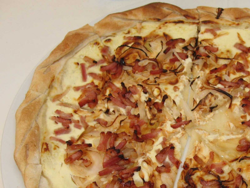 «Тарт фламбе» — хрустящая пицца из Эльзаса со сметаной, тонко нарезанным луком и кусочками сала или бекона.