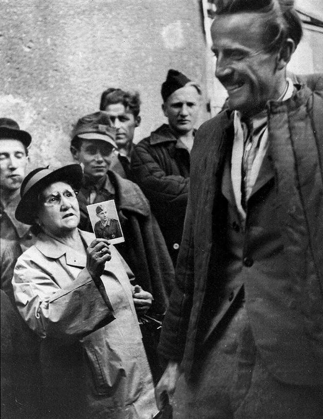 45. Мать показывает фотографию своего сына возвращающимся военнопленным, пытаясь отыскать его. Вена, 1947 год.